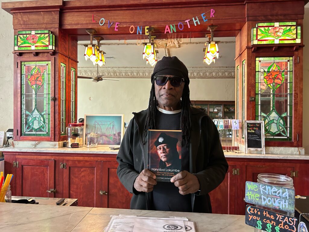 Hannibal Lokumbe holding his book at Tough Cookie Bakery.