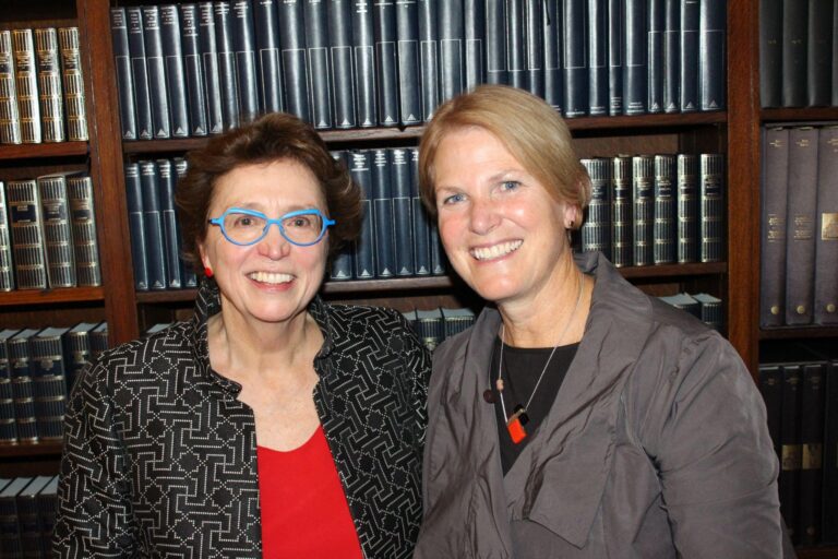 A photo of two women standing in front of a bookshelf