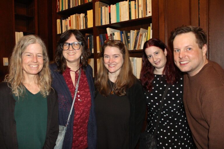 A group of five people standing in front of a bookshelf