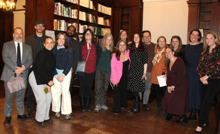 A group photo of a 16 people in a library