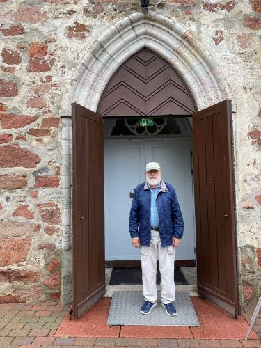 Markes E. Johnson stading in the Portal to Saint Olaf Church in Jomala with its unique limestone construction distinct from red Rapakivi granite.